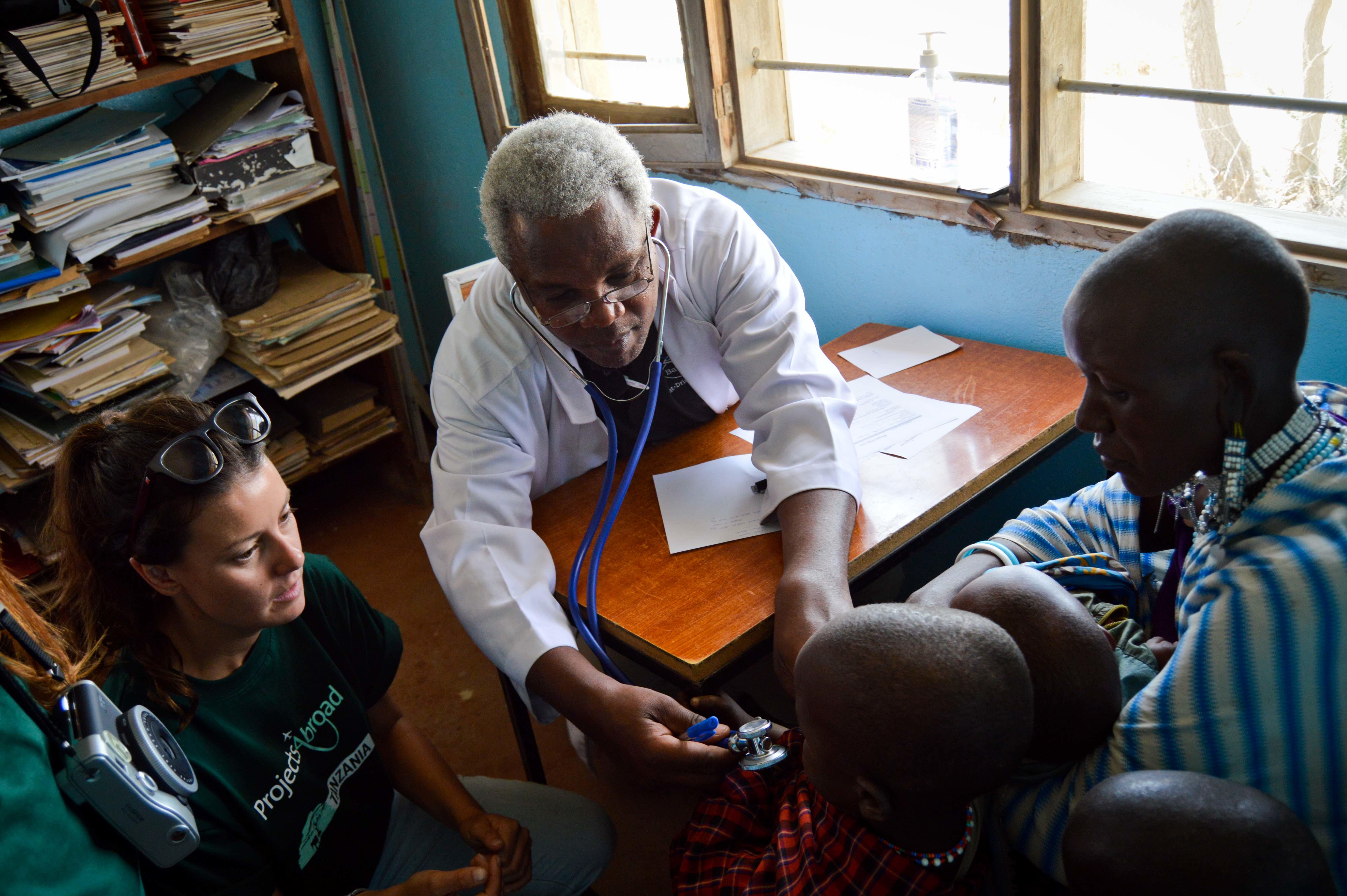 A Dentistry intern watches a local doctor do a health check at a clinic in Tanzania. A student doing a Dentistry internship in Tanzania observes a local doctor as he performs a health check for a child.